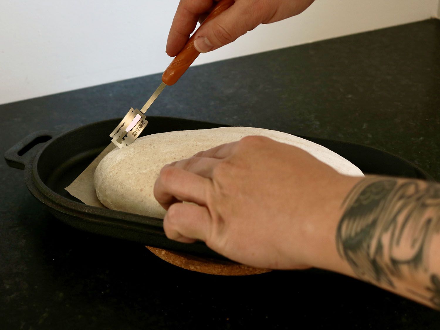 一个面包面团正被绑在面包腿上的剃须刀片划破。