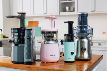 four juicers on a wooden countertop