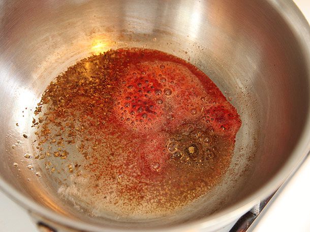 在银色平底锅中放入油，将achiote，孜然和牛至烤出香味。