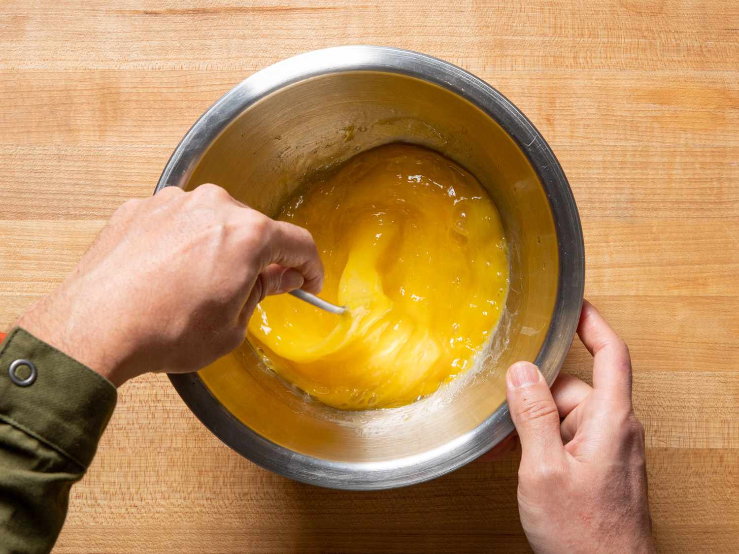 用打蛋器在金属碗里搅拌鸡蛋。