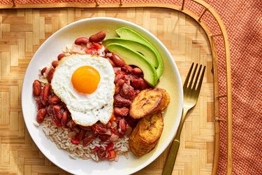 俯视图哥伦比亚豆子和米饭在一个盘子和一个木托盘煎鸡蛋