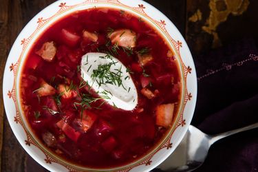 Overhead shot of a bowl of Ukrainian borscht topped with a dollop of sour cream and sprinkling of fresh dill