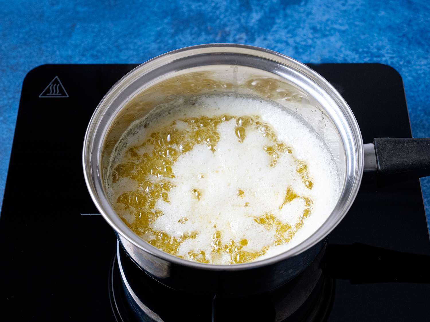 一锅煮熟的黄油，上面放着破碎的白色牛奶蛋白