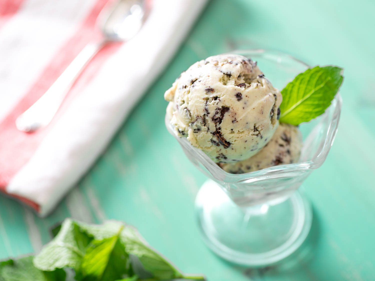 一盘薄荷巧克力片冰淇淋，新鲜的薄荷叶在薄荷绿色的背景