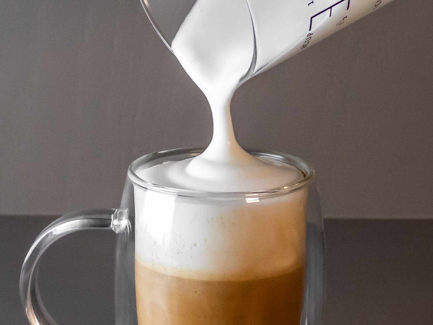 牛奶泡沫被倒进咖啡杯的特写镜头