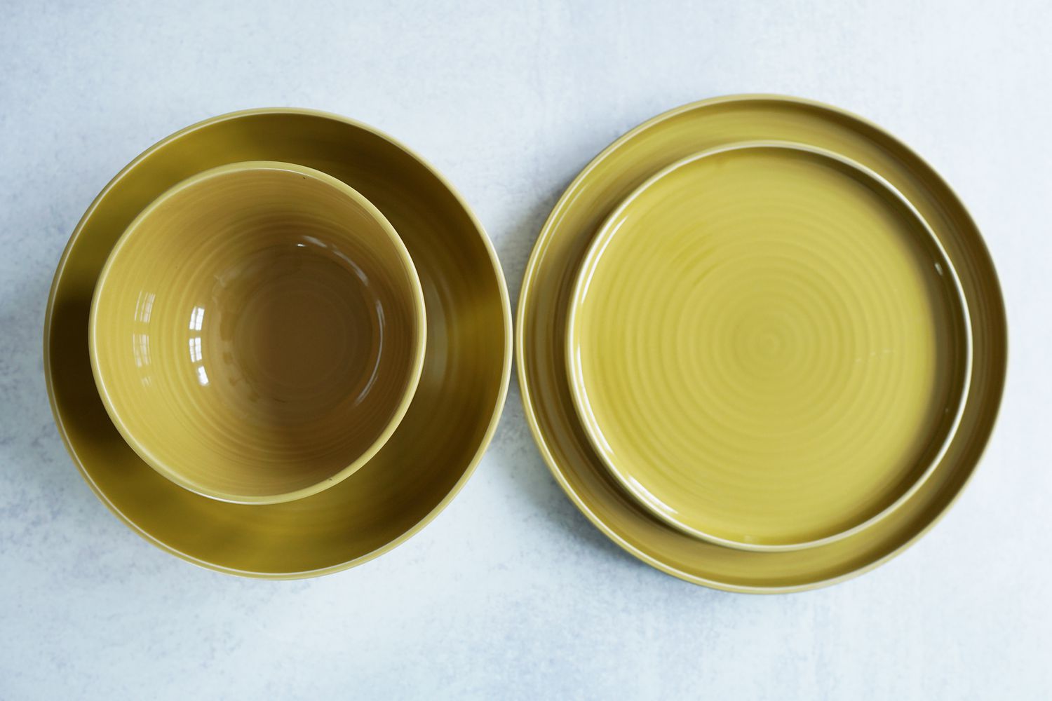 Two yellow plates and two bowls on a grey surface