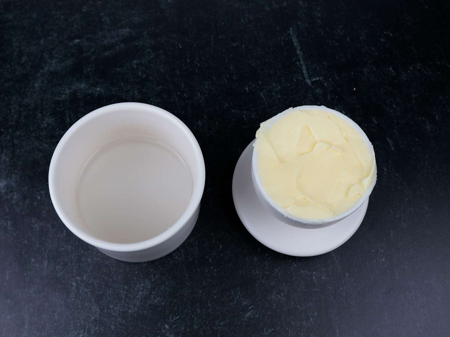 一个陶瓷黄油罐的两面放在柜台上，一半装水，一半装黄油