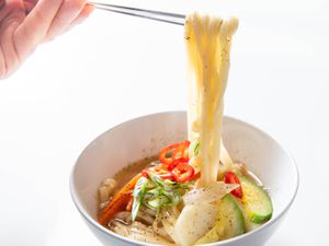 一碗韩国刀切面条汤,筷子下面提高面条的碗。