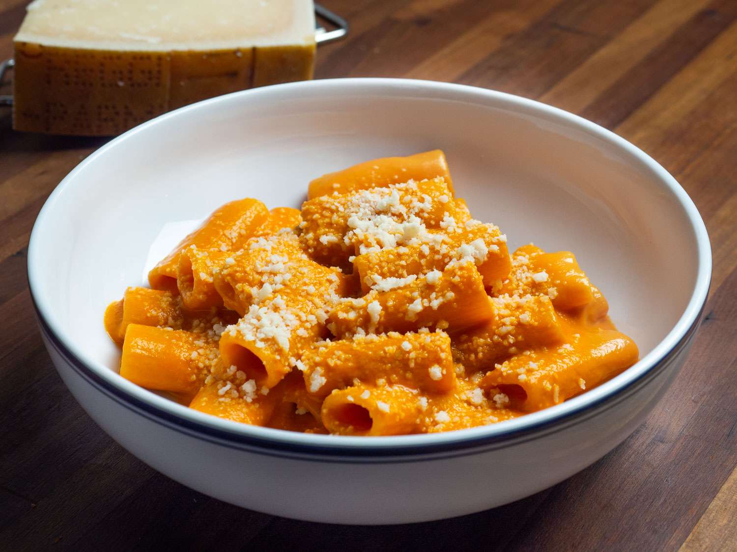 A white bowl of penne alla vodka sprinkled with cheese
