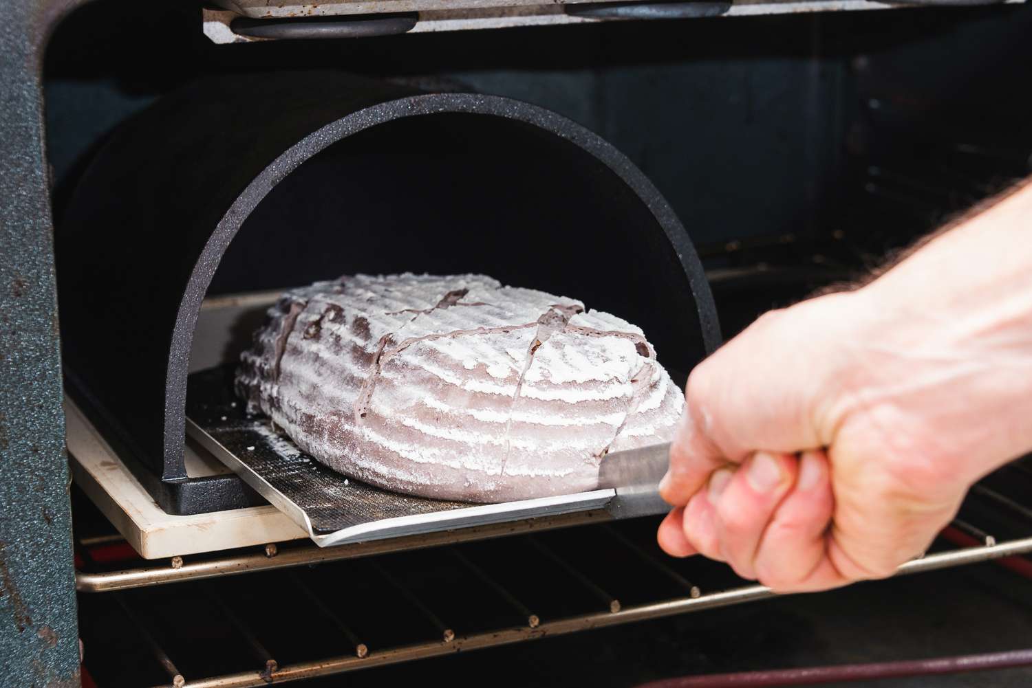 一只手将一块面包放到烤箱里的面包船