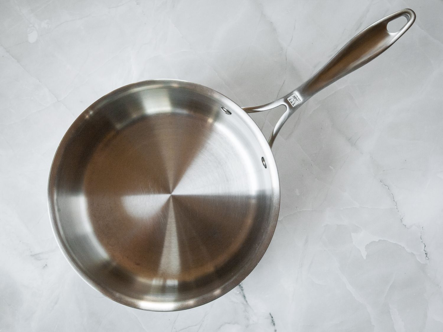 A stainless steel saucepan on a marble countertop