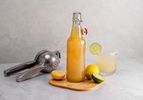 一瓶酸混合与柠檬木砧板,切片柠檬、柑橘榨汁器,和玻璃混合饮料。