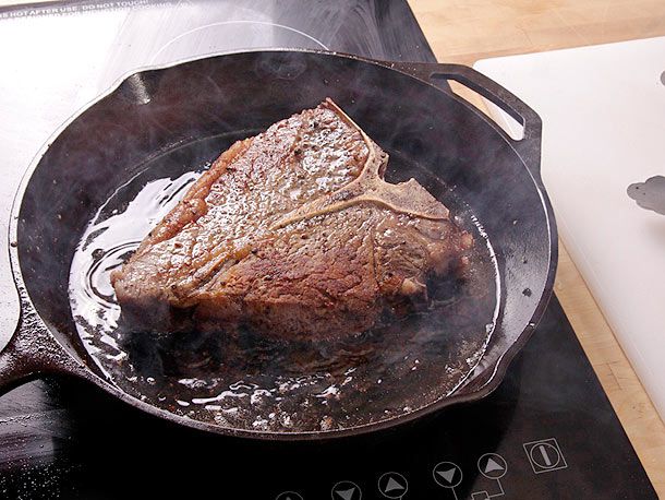 在铸铁煎锅中，在冒烟的油中烤着的上等腰牛排。