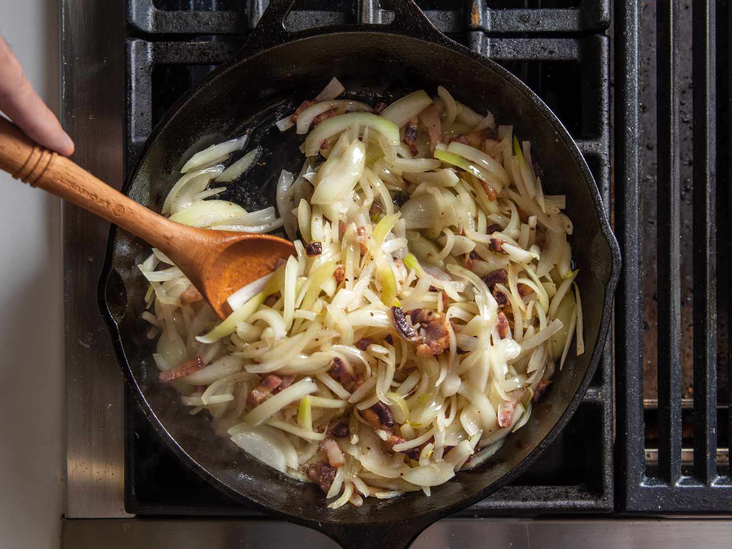 切好的洋葱和培根一起放在铸铁煎锅里煮。