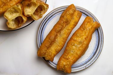 Youtiao on a plate next to a platter of youtiao