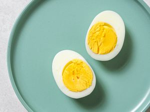 一个完美的蒸熟鸡蛋，纵向切成两半，放在一个蓝色的盘子上。