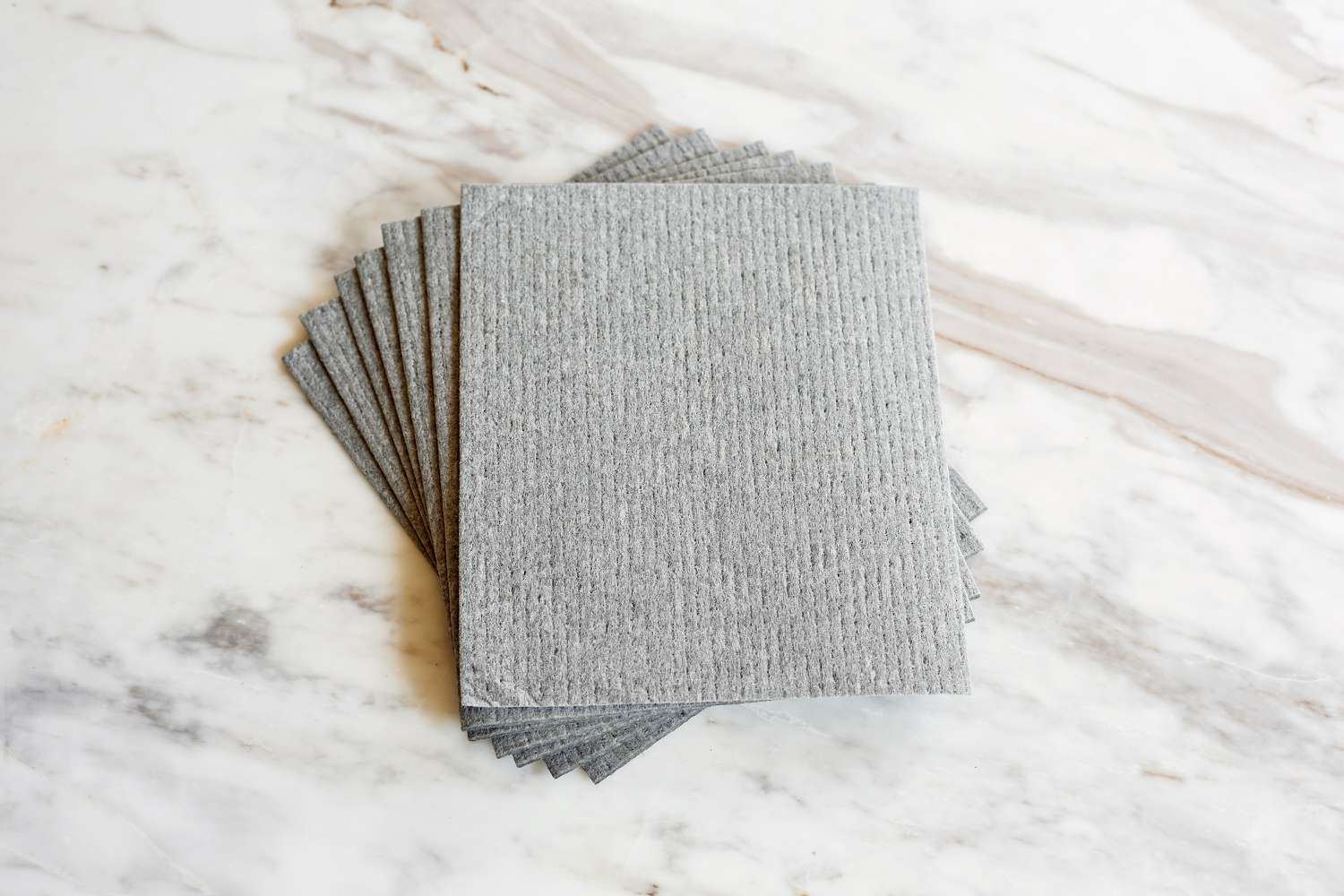 a stack of grey swedish dishcloths on a marble surface