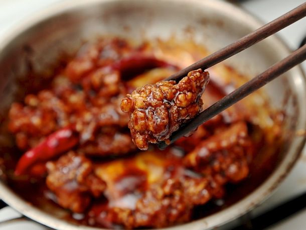用筷子夹起一块左宗棠鸡放在煎锅上。gydF4y2Ba