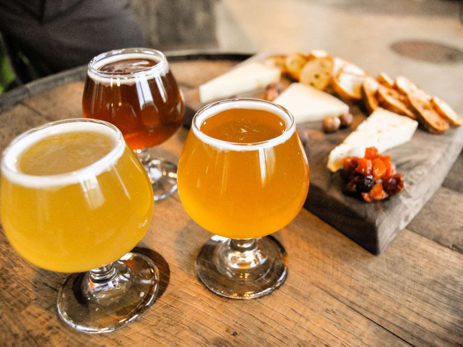 三种不同的啤酒放在玻璃杯里，旁边是奶酪板。