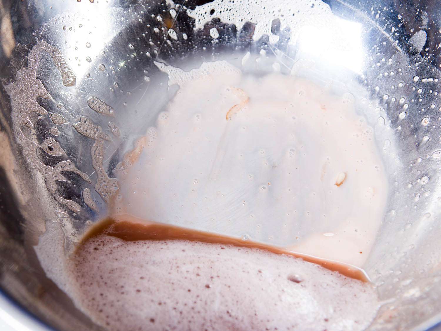 棕色的水和含水的土豆淀粉在一个金属搅拌碗的底部gydF4y2Ba