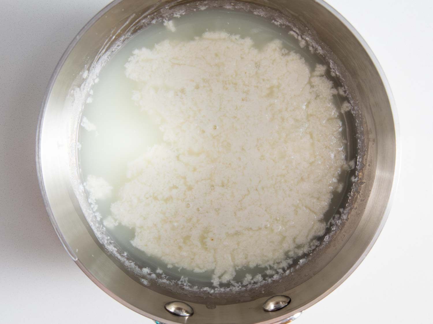 凝乳在不锈钢锅中与乳清分离。