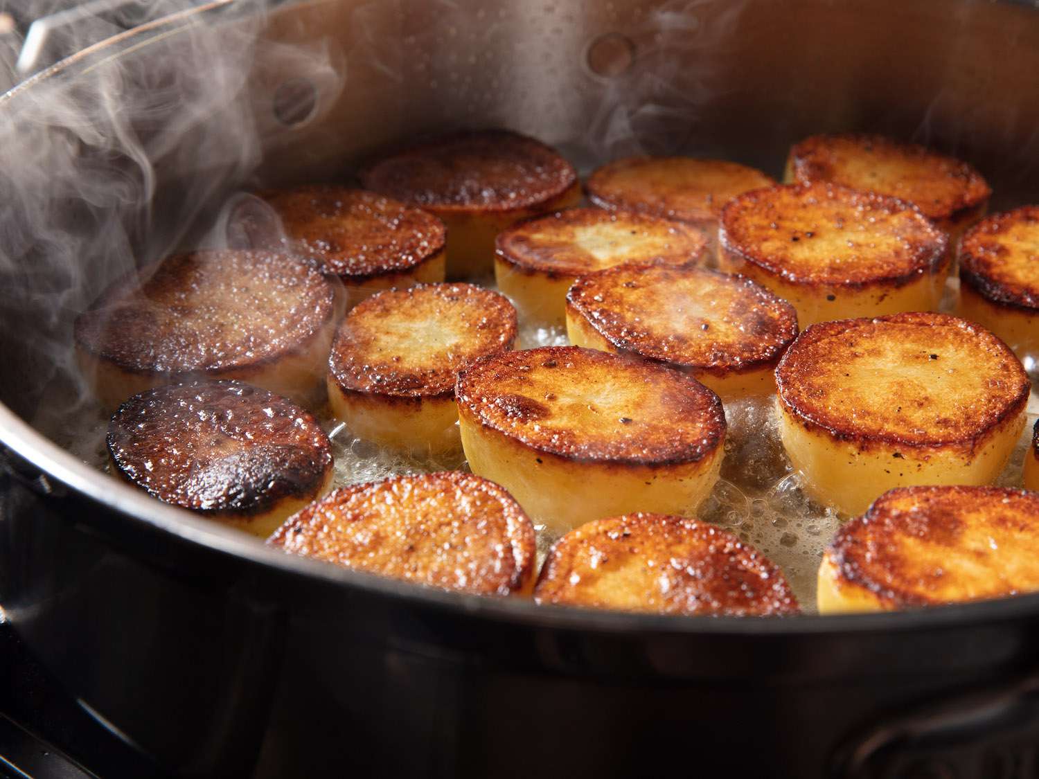 平底锅里的土豆一侧烤焦，黄油起泡。