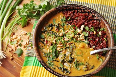 Overhead of a bowl of vegan peanut, sweet potato, and coconut soup with red rice