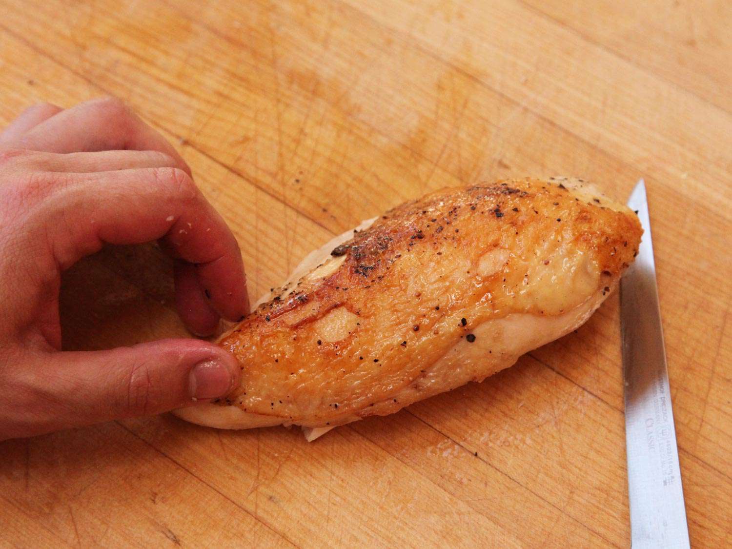 鸡胸肉,煮熟的真空和完成加热,一个木砧板一把刀