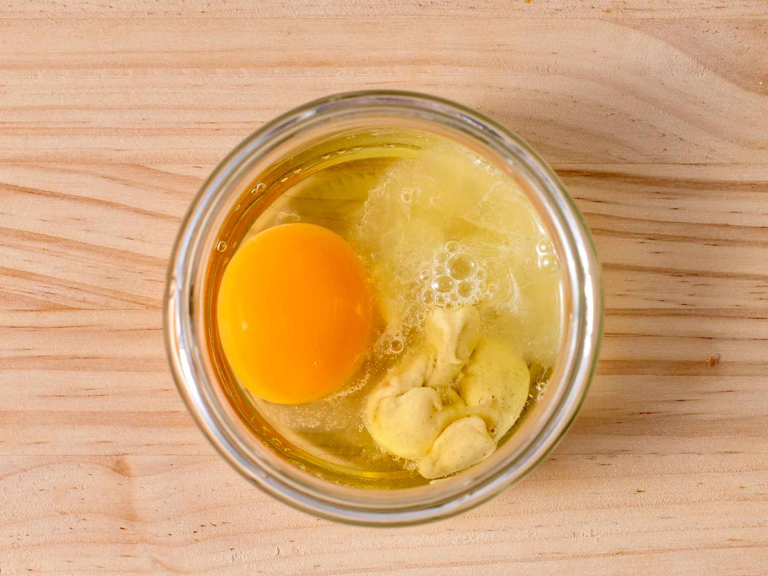 鸡蛋、柠檬汁和芥末放在一个玻璃罐子的底部，罐子的大小刚好能装下浸入式搅拌器的头。