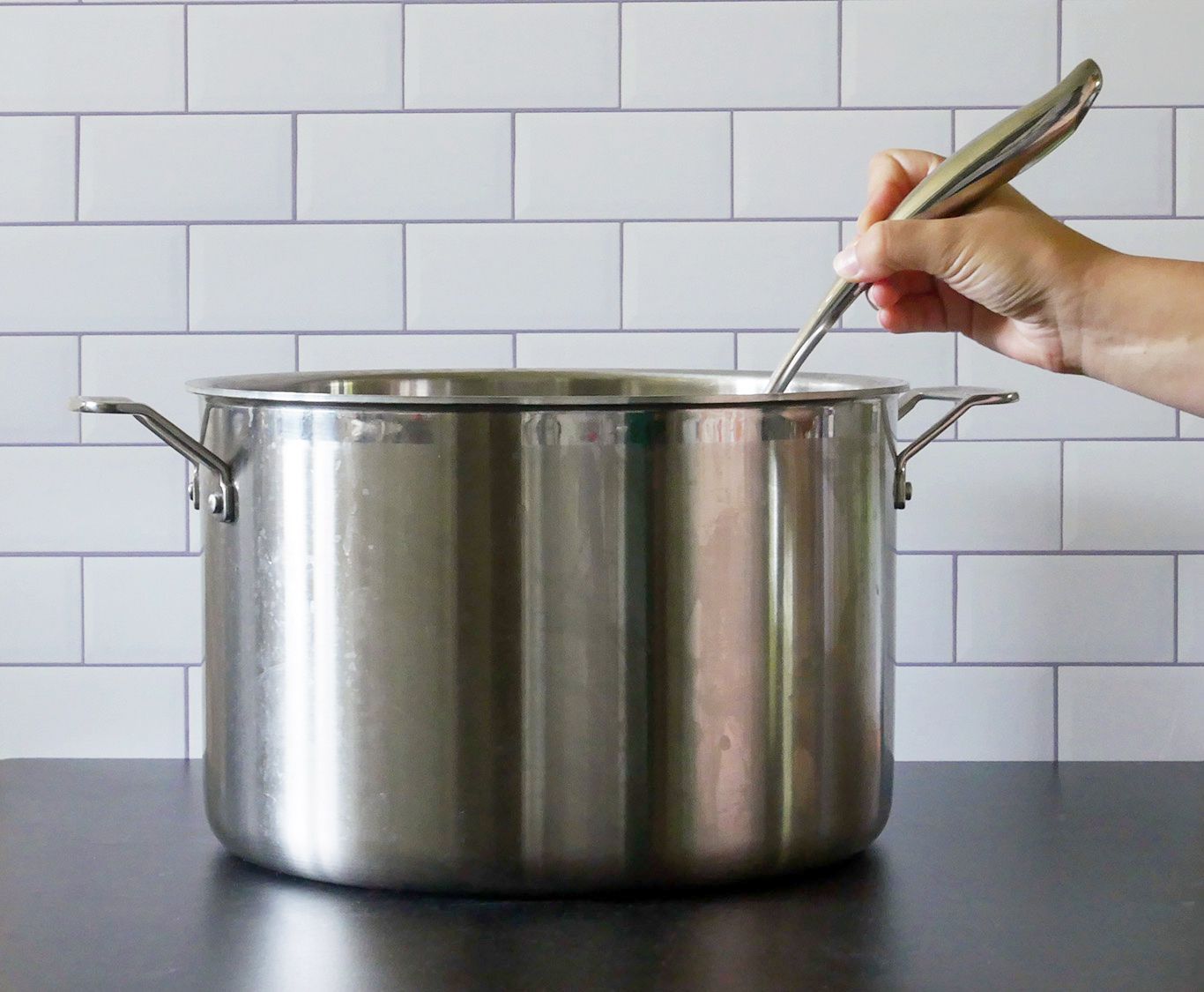 烹饪艺术的勺子被放在锅里，以显示手柄的曲线