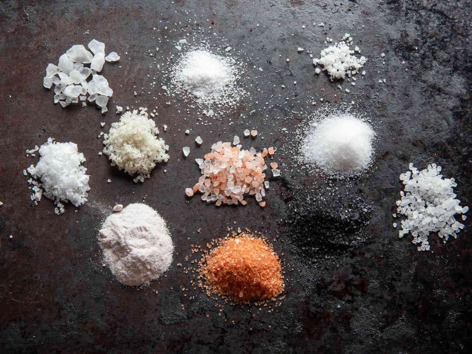 成堆的不同品种的盐，以显示颜色，质地和大小的差异