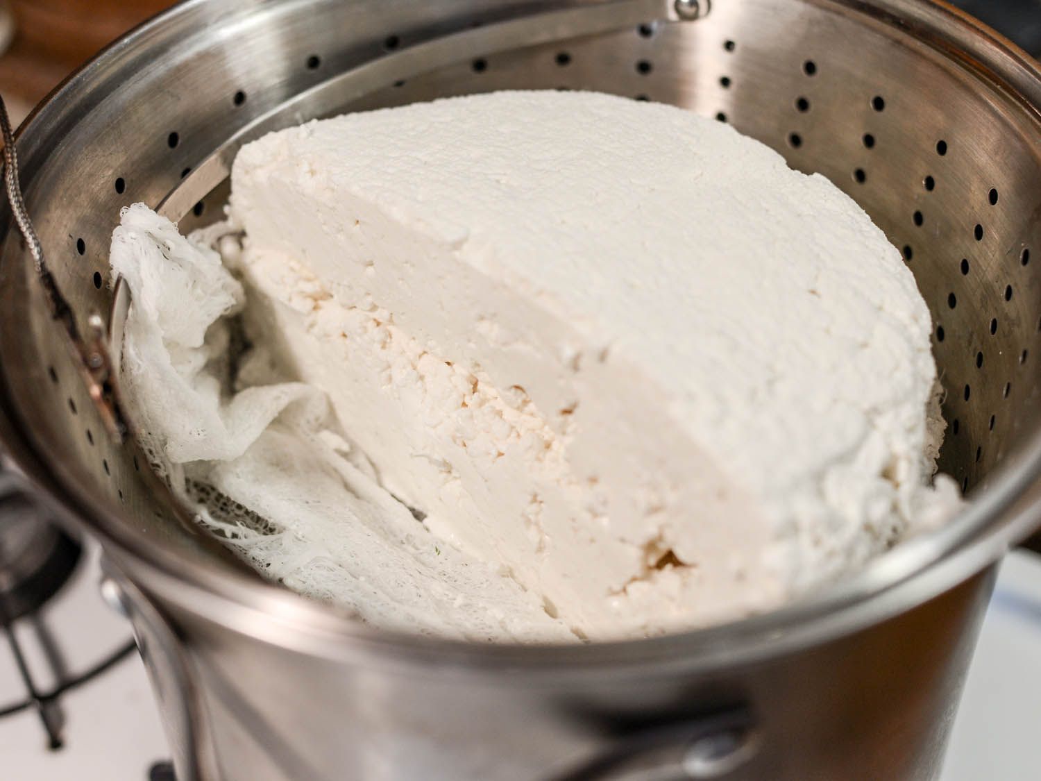 干酪凝块在蒸笼中沉淀，插入一锅热乳清。
