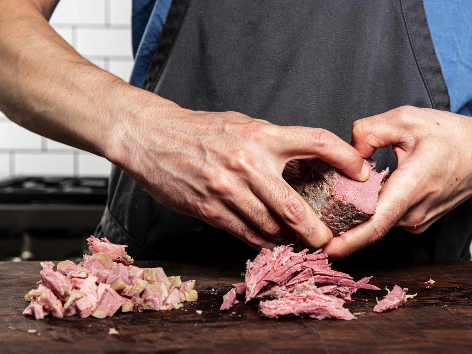 双手把腌牛肉在砧板上撕成一堆