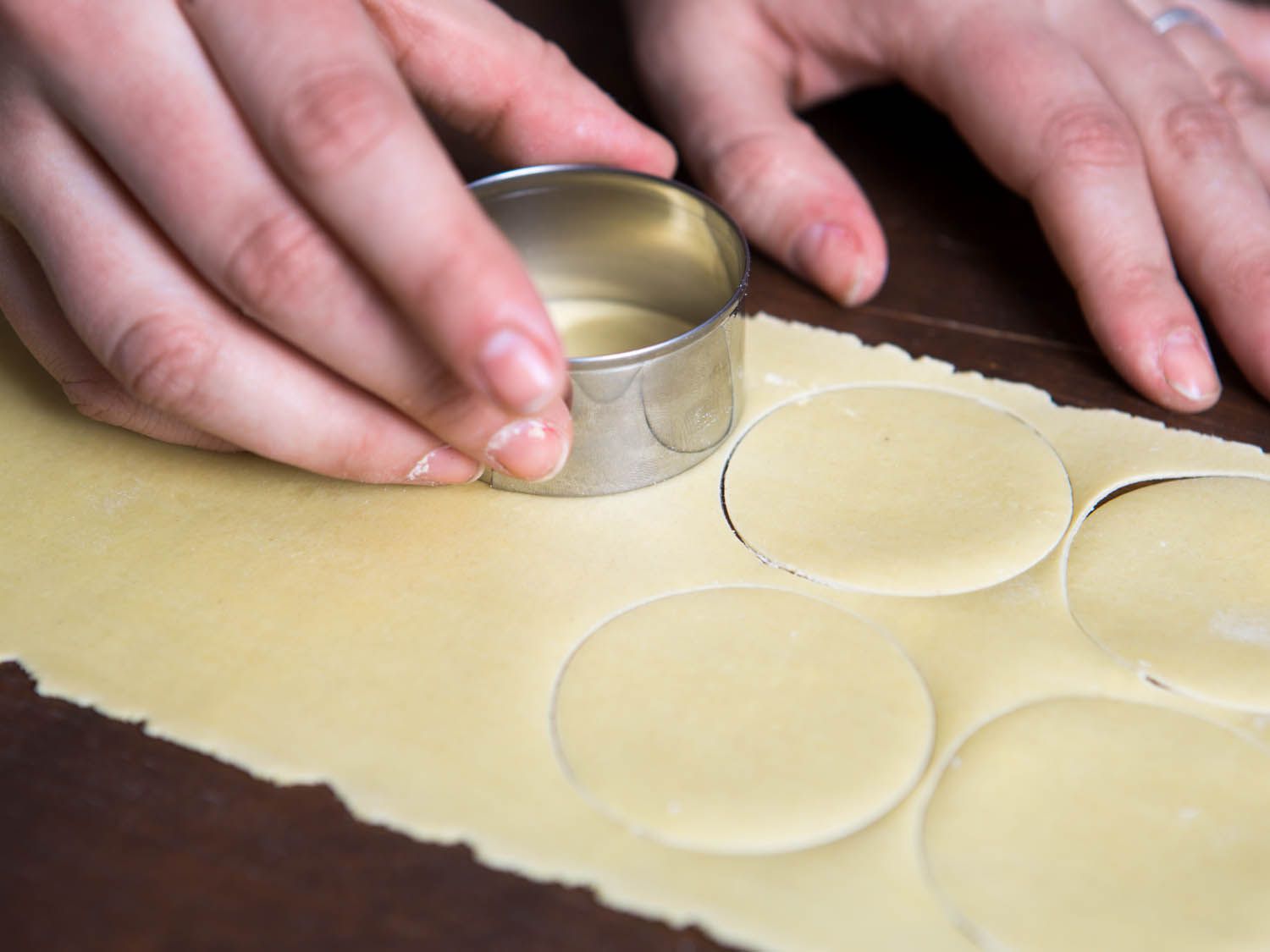 a person using a cutter to stamp circles out of pasta dough