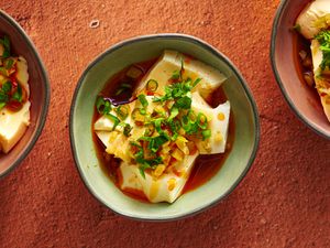 豆腐碗一种不规则的圆形上釉陶瓷碗，盛有酱油和辣椒油的丝豆腐还有两个额外的碗，一个在图像的右边外围，一个在左边外围。