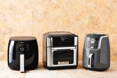 three air fryers side-by-side on a biege countertop