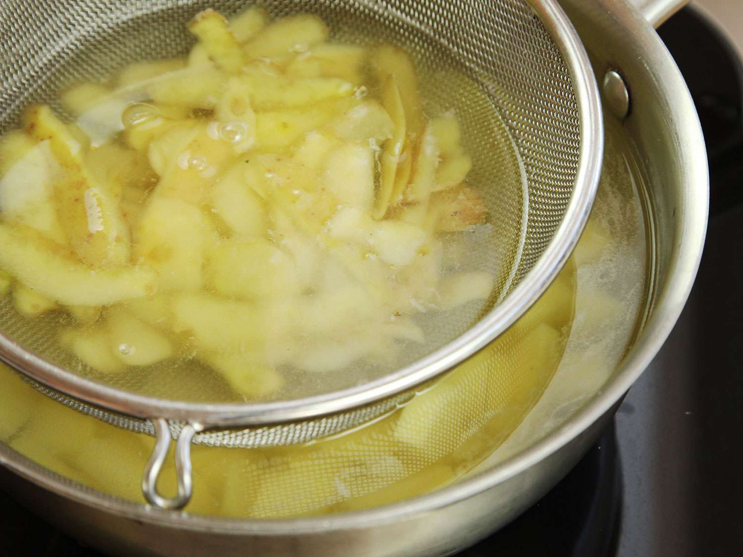 将去皮切片的土豆和土豆皮放在锅顶的网状过滤器中烹饪。gydF4y2Ba