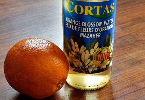 一瓶橙花水和一个橙色的旁边。