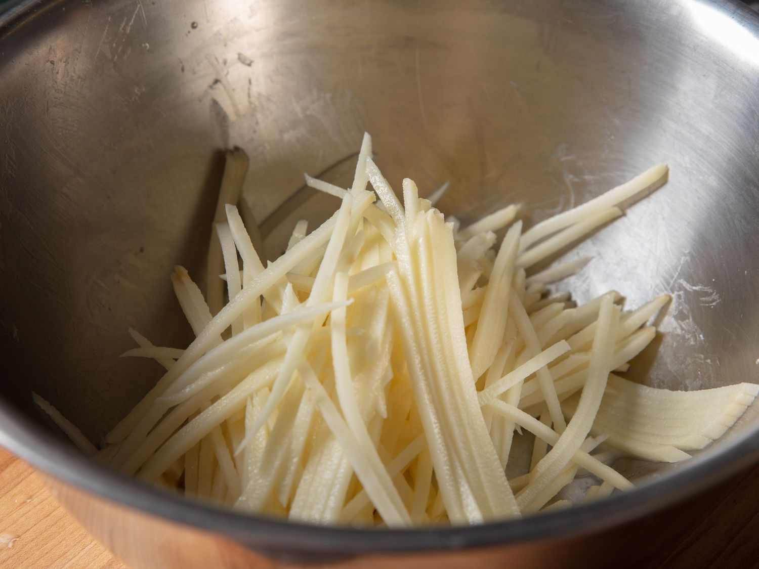 在搅拌碗里切成丝的生土豆。