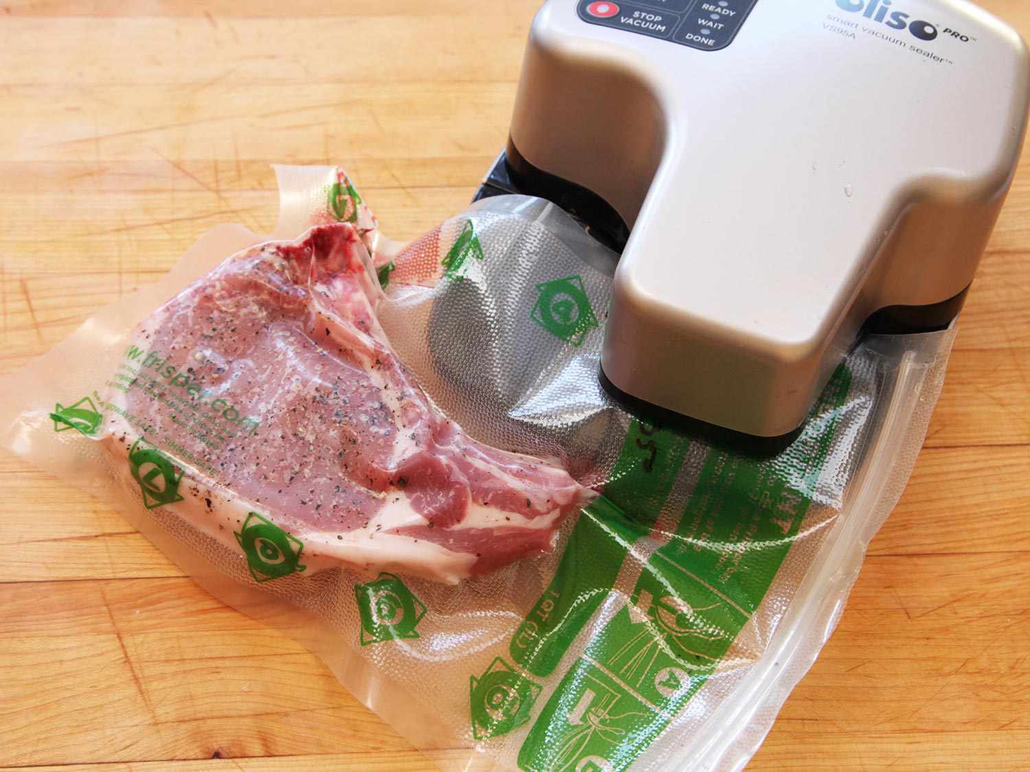 Sealing a seasoned bone-in pork chop in a vacuum-seal bag before cooking sous vide.