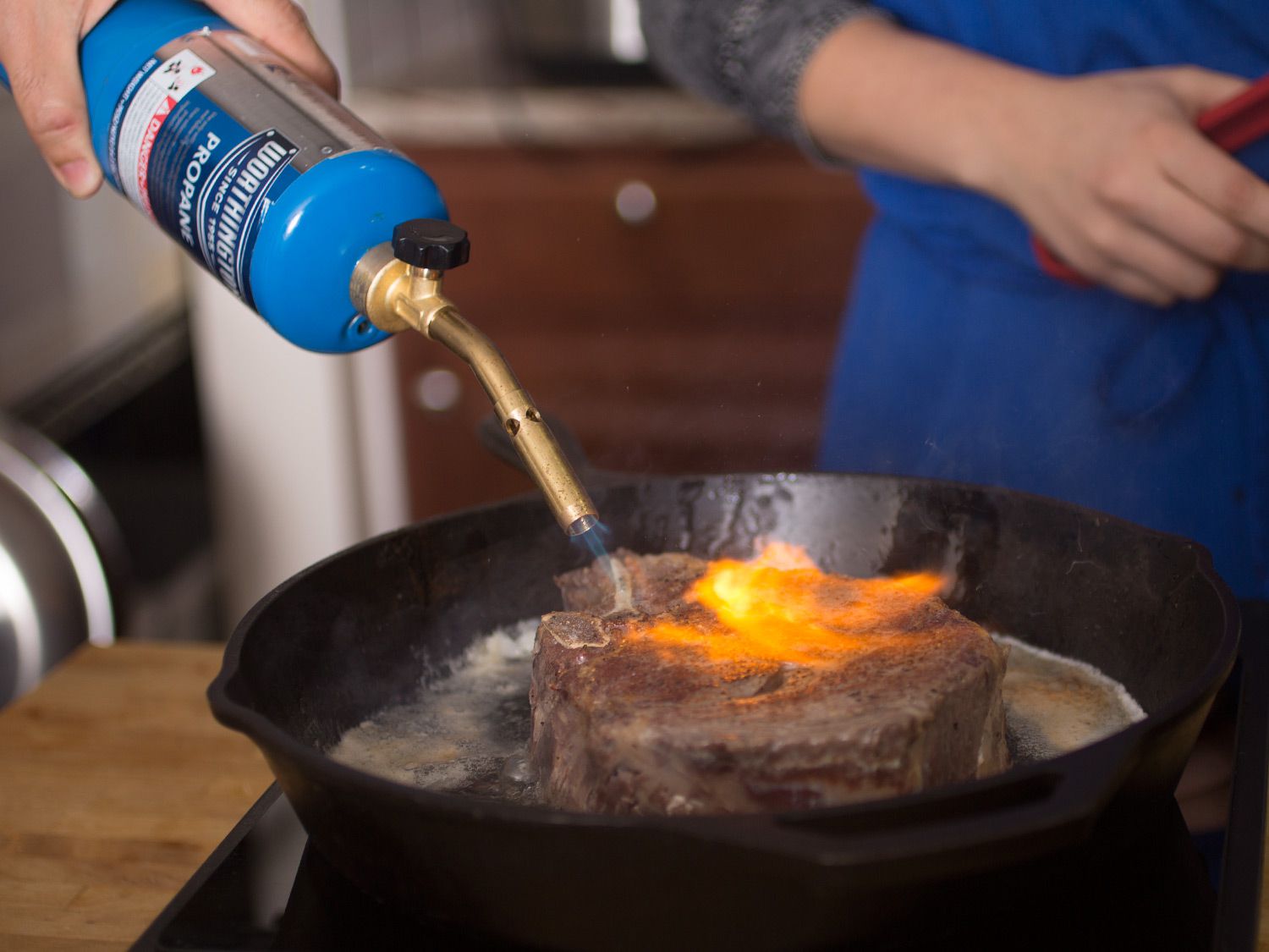 一个丙烷火炬灼热的铸铁盘牛排。