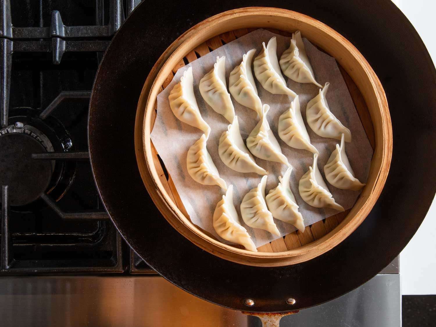 俯视图的饺子在羊皮纸内衬的竹蒸笼设置在锅。