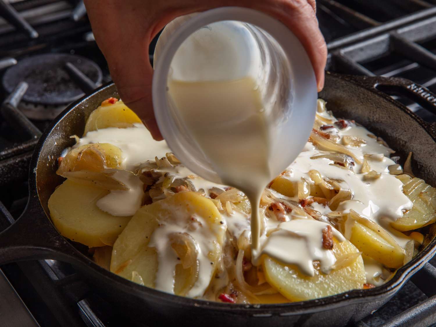 在煎锅里把奶油倒入土豆和洋葱中。