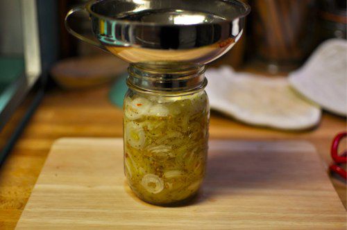 葱和盐水转移到一品脱jar的帮助下一个罐头漏斗。