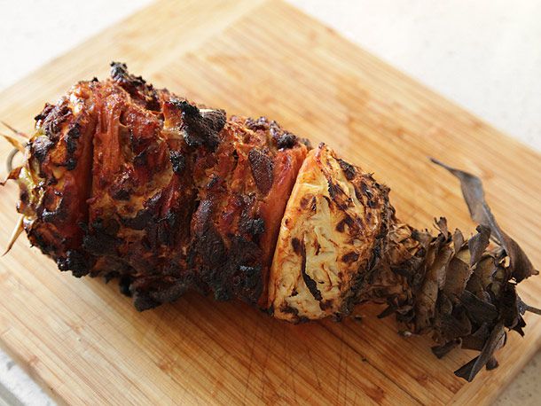 烤猪肉串在菠萝里，顶部和底部放在木砧板上。
