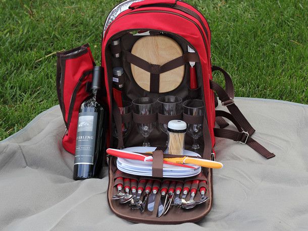 红色野餐背包里面显示了牙签,盘子,眼镜,和器皿内,还有一瓶酒。