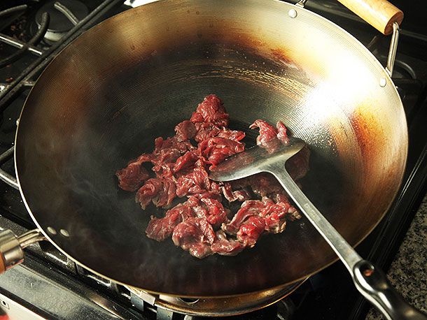 切成薄片并腌制的裙装牛排放入调味的碳钢锅中。
