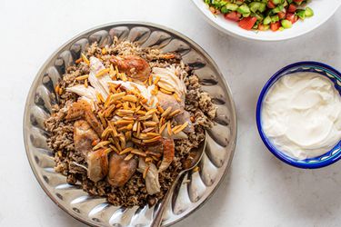 Hashweh with chicken served with a bowl of yogurt and farmers salad.