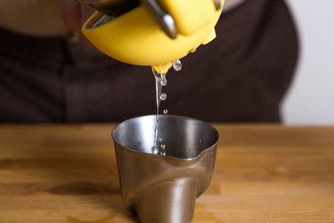 从一个柠檬汁被挤到一个小金属量杯。