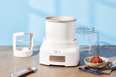 Cuisinart 1.5-Quart Frozen Yogurt, Ice Cream, & Sorbet Maker on a wooden surface with a bowl of ice cream beside it